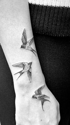 a woman's wrist tattoo with three birds flying in the sky on her left hand