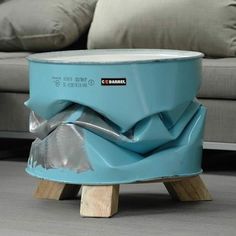 a blue stool sitting on top of a hard wood floor next to a gray couch