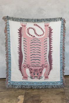 a pink and blue rug with an animal design on the front, sitting on a wooden floor