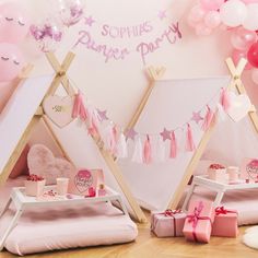 a pink and white birthday party setting with balloons, presents and teepees on the floor