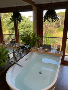 a large white bath tub sitting on top of a wooden floor next to a window