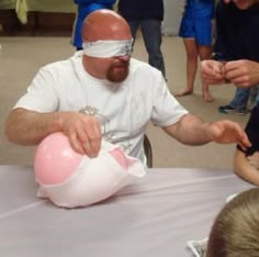 a man with blindfolded head sitting at a table in front of other people