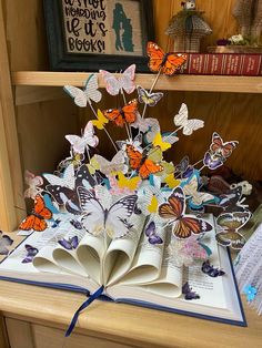 an open book sitting on top of a table filled with butterflies