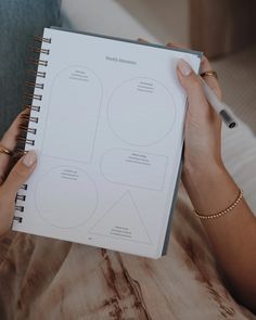 a person is holding a notebook with diagrams on the cover and pen in their hand