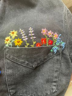 the back pocket of a jean jacket with flowers embroidered on it