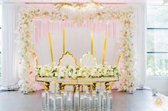 a table with cake and candles on it in front of a floral decorated stage backdrop