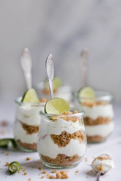 three small desserts with lime slices and whipped cream in them on a white table