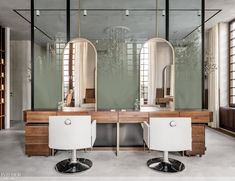 two white chairs sitting in front of a mirror on top of a counter next to mirrors