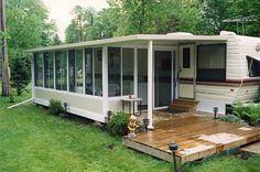 a mobile home sits in the middle of a grassy area with steps leading up to it