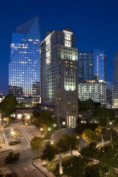 the city skyline is lit up at night with skyscrapers in the backround