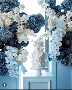 a white and blue wedding cake sitting on top of a table next to some flowers