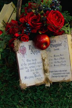 an old book with roses and apples on it next to a basket filled with flowers