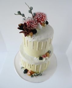 a three tiered cake with flowers on the top and bottom, sitting on a white plate