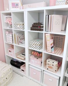 a white bookcase filled with lots of pink and white boxes on top of it