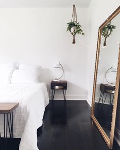 a bedroom with a bed, mirror and side table