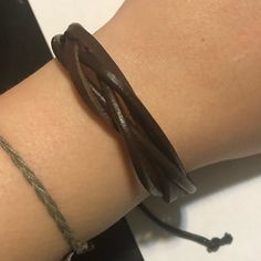 a close up of a person's arm wearing a bracelet with two braids on it