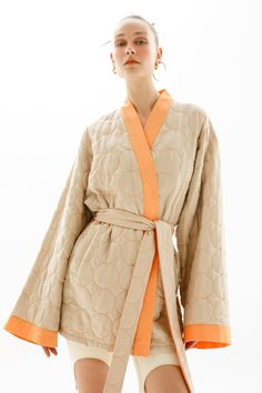 Colour: beige with orange trim and contrast- ing threads Fabric: Main fabric is 100% vegan silk, lining is 100% cotton Opening system: strings at the waist Details: vegan silk quilted kimono-dress with contrasting trim, drop shoulder, separate belt, long wide sleeves, tied waist, after thigh-length, two side slash pockets, apple leather logo tag. Apple Leather, Silk Quilt, Contrasting Trim, Colour Beige, Kimono Dress, Wide Sleeves, Contrast Trim, Dress First, Drop Shoulder