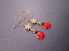 Pretty little gold ladybug charms (9x12mm) with red and black enamel lacquer, dangle from tiny (7mm) white and yellow enameled daisy connectors, on gold french hook ear wires. These earrings measure one and 1/2 inches in length See more of my designs here; justEARRINGS.etsy.com And please visit my sister~shops; justCHARMING.etsy.com & BohoDreamJewelry.etsy.com All of my jewelry shops offer FREE SHIPPING! Highlights: handmade jewelry, ladybug and daisy earrings, gold charms, red and black, wh Red Novelty Drop Earrings, Cute Enamel Drop Earrings Jewelry, Cute Enamel Drop Earrings, Cute Red Enamel Earrings, Cute Red Dangle Jewelry, Red Enamel Drop Earrings, Red Enamel Dangle Earrings, Red Enamel Jewelry With Charms, Red Novelty Jewelry With Charms