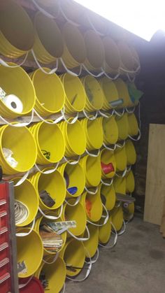 yellow buckets are stacked up on the wall in a storage room with other items