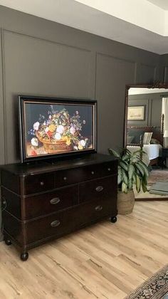 a tv sitting on top of a wooden dresser