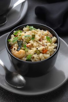 a bowl filled with rice and vegetables on top of a plate next to a cup