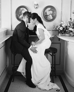 a bride and groom sitting on a stool in the corner of a room with floral arrangements