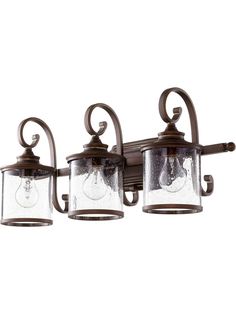 three light bathroom fixture with clear glass shades on the top and bottom lights in an antique bronze finish