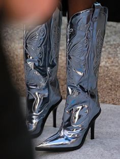 a close up of a woman's silver boots on the ground with her legs crossed