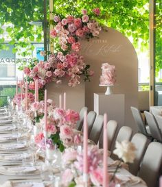 a long table is set with pink flowers and candles for an elegant wedding reception at the park