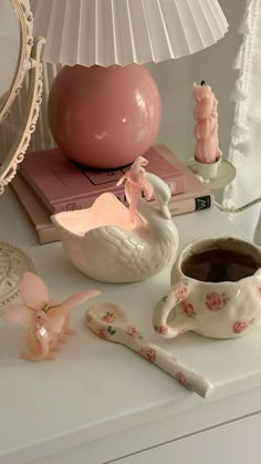 a white table topped with a cup of coffee next to a lamp and other items