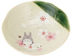 a plate with a totoro and flowers painted on the side, in front of a white background