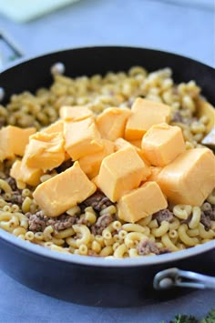 a skillet filled with macaroni and cheese on top of a blue table