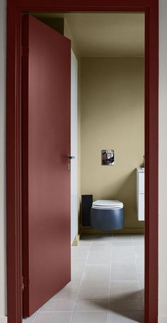 an open door leading to a bathroom with a toilet in the corner and red painted walls