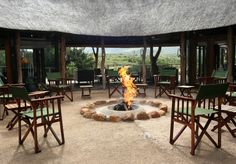 a fire pit surrounded by chairs and tables in the middle of an open air area