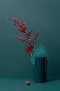 a green vase with red flowers in it