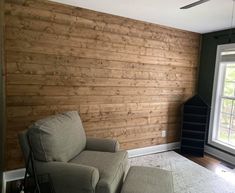 a living room with wood paneling on the wall and a chair next to it