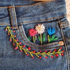 a pair of jeans with embroidered flowers on them