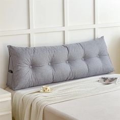 a white bed with a gray pillow on top of it