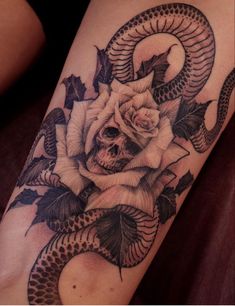 a woman's thigh with a rose and snake tattoo on the side of her leg