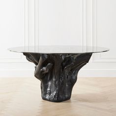 a glass table sitting on top of a hard wood floor next to a white wall