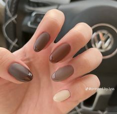 a woman's hand with some brown and white nail polishes on her nails