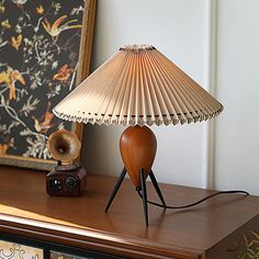 a lamp sitting on top of a wooden table next to a framed photograph and an old camera