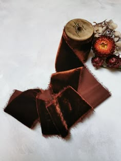 a piece of brown ribbon next to some dried flowers