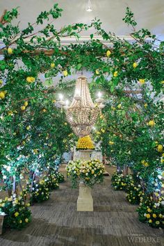 a room filled with lots of flowers and greenery next to a chandelier