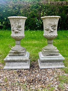 two stone vases sitting on top of each other in front of some green grass