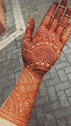 a hand with henna on it is shown in front of a brick walkway and sidewalk