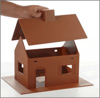 a hand is holding the roof of a toy house that has been made out of cardboard