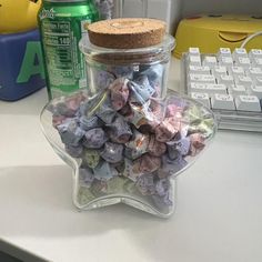 a glass jar filled with candy sitting on top of a desk next to a keyboard