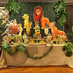 the lion king birthday party table is set up with decorations and jungle animals on it