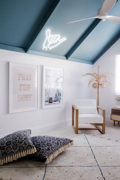 a living room with white walls and blue ceilinging, two framed pictures on the wall